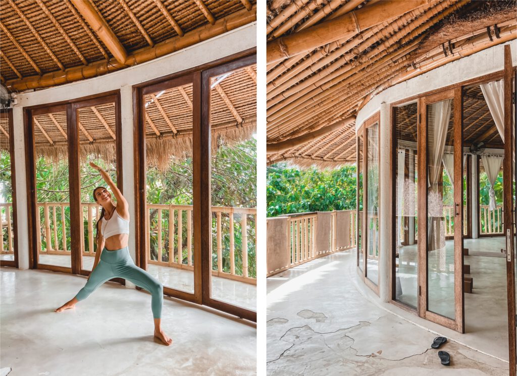 A young woman practicing yoga in a light flooded bamboo studio with a white floor and panoramic windows.