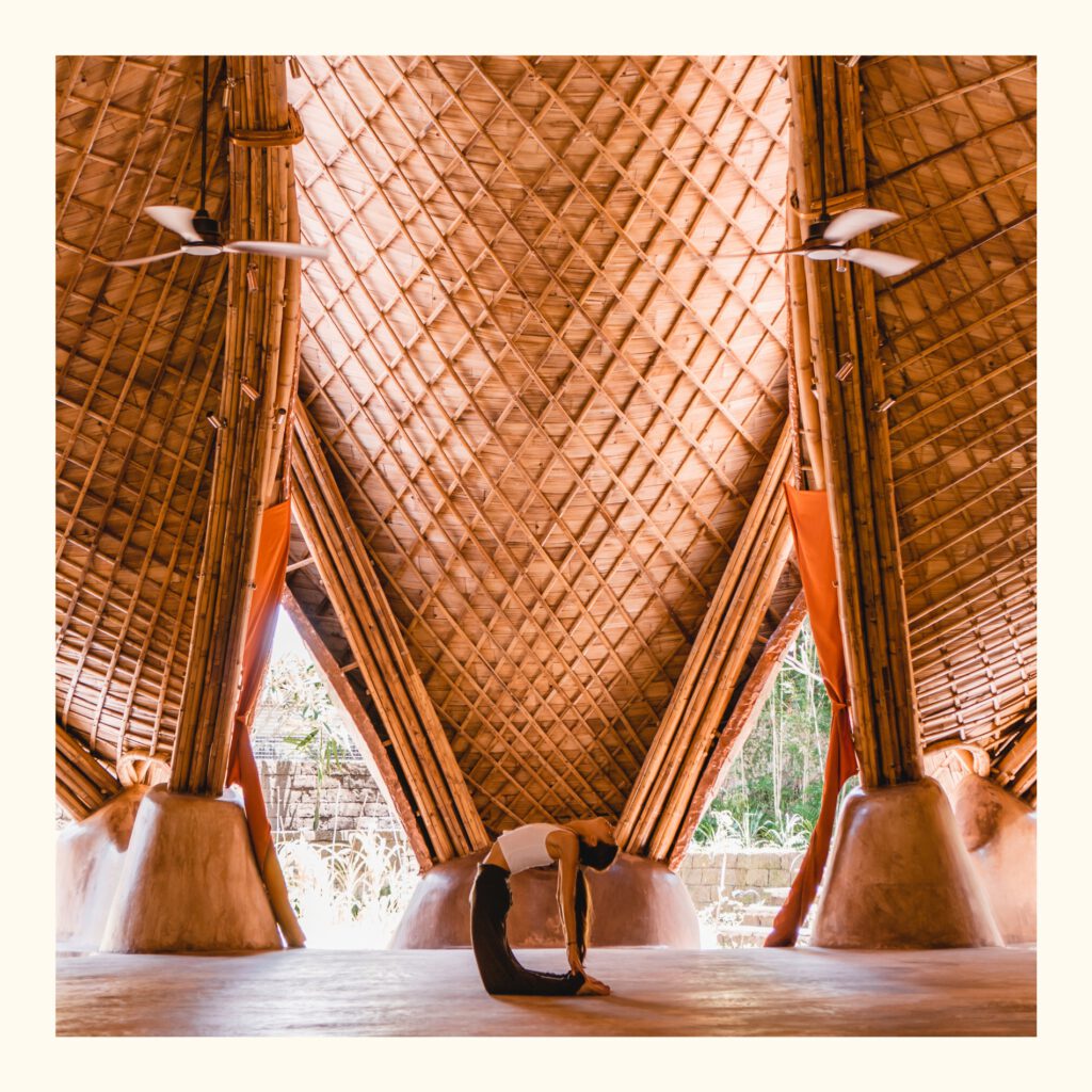 A woman practicing yoga in the bamboo yoga shala of Alchemy Yoga & Meditation Center in Ubud.