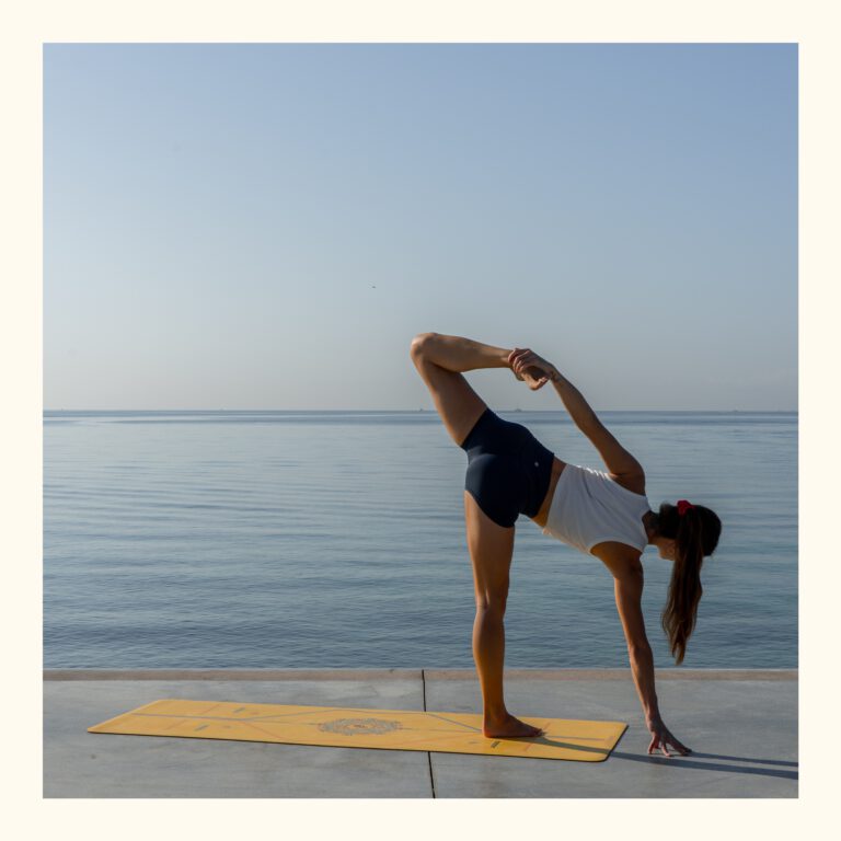 Young woman practicing yoga on a sunny day right by the Mediterranean sea on Mallorca.