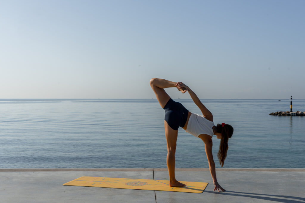 Young woman practicing yoga on a sunny day right by the Mediterranean sea on Mallorca.